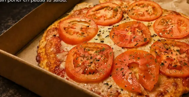 Pizza con masa de pollo y rodajas de tomate en su caja de cartón